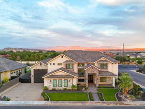 View of front of house featuring driveway, stucco siding, a garage, and stone siding
