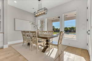 Dining area with light wood-style flooring, a ceiling fan, and a chandelier