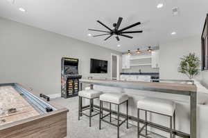 Kitchen with a kitchen bar, white cabinetry, light carpet, a ceiling fan, and recessed lighting