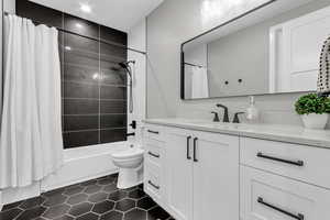 Bathroom with shower / tub combo with curtain, vanity, and dark tile patterned flooring