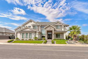 View of front facade with stone siding, stucco siding, and a front yard