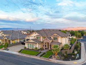 View of front of home with stucco siding, stone siding, a residential view, driveway, and a mountain view