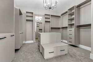 Spacious closet featuring a chandelier and light colored carpet