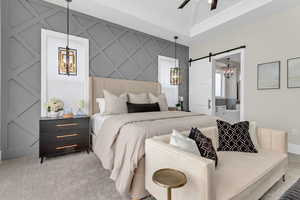 Bedroom with a chandelier, a barn door, an accent wall, light colored carpet, and ensuite bathroom