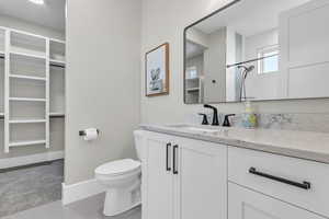 Full bathroom featuring a spacious closet, vanity, and a shower
