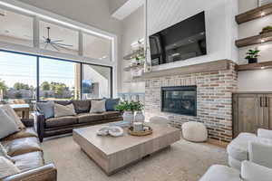 Living room with a fireplace, a towering ceiling, and a ceiling fan