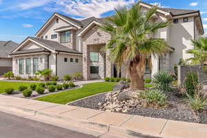 View of front of property with stone siding, stucco siding, a front lawn, and a tiled roof