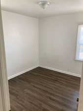 Spare room featuring dark wood finished floors and baseboards