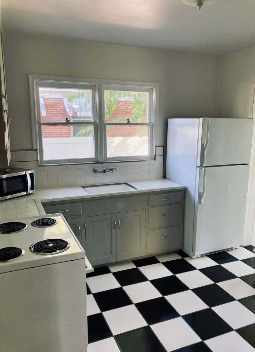 Kitchen featuring black and white checkered flooring, light gray cabinetry, and a white tile backsplash