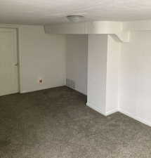 Unfurnished room with dark carpet and a textured ceiling
