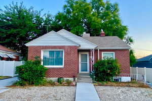 Bungalow-style home featuring brick siding, a chimney, and roof with shingles