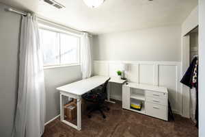 Office with a wainscoted wall, a decorative wall, and dark carpet