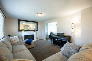 Carpeted living area featuring a glass covered fireplace and baseboards