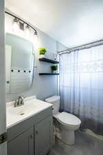 Full bathroom with a shower with shower curtain, vanity, a textured ceiling, and dark tile patterned flooring