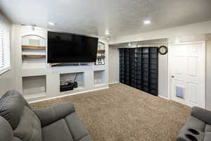 Carpeted living room featuring a textured ceiling, built in features, and recessed lighting