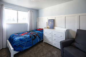 Bedroom featuring carpet floors, a decorative wall, and a textured ceiling