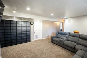 Carpeted home theater room with a textured ceiling and recessed lighting