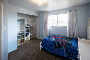 Bedroom featuring a textured ceiling, dark colored carpet, and a closet