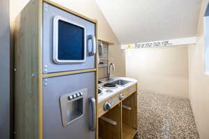 Kitchen featuring a textured ceiling, lofted ceiling, and stainless steel microwave
