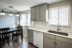 Kitchen featuring gray cabinets, dishwasher, light stone countertops, tasteful backsplash, and a textured ceiling