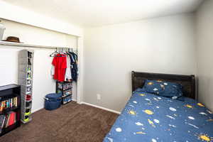 Carpeted bedroom with a textured ceiling and a closet