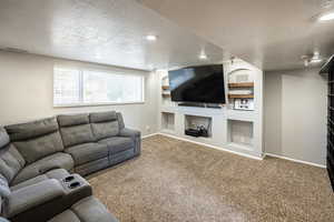 Carpeted living area featuring a textured ceiling, built in shelves, and recessed lighting
