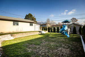 View of yard featuring a playground and an outbuilding