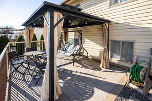 Wooden deck featuring a gazebo and outdoor dining space