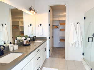 Full bath with a walk in closet, double vanity, light carpet, and a shower stall