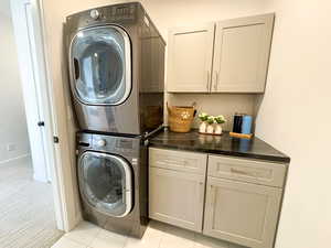 Spacious private laundry with stacked washer and dryer  with custom cabinets for storage