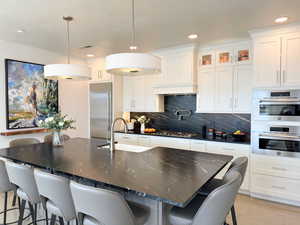 Beautiful kitchen includes stainless steel appliances, and beautiful black quartz countertops and backsplash
