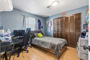 Bedroom featuring wood finished floors, a closet, and an office area