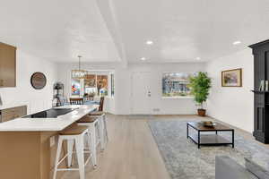 Living area with recessed lighting, a textured ceiling, healthy amount of natural light, light wood-style floors, and a decorative wall