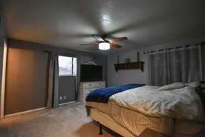 Carpeted bedroom with ceiling fan and a textured ceiling