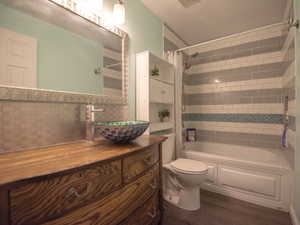 Full bathroom with shower / bath combo with shower curtain, vanity, and dark wood-type flooring