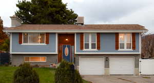 Bi-level home featuring concrete driveway, an attached garage, and stucco siding