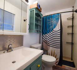 Bathroom with tiled shower, vanity, and tasteful backsplash