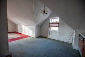 Bonus room featuring vaulted ceiling, carpet flooring, a textured ceiling, and a chandelier