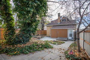 Rear view of house with a chimney, a fenced backyard, a patio, and brick siding