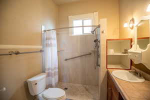 Full bathroom featuring vanity, a stall shower, and a textured wall