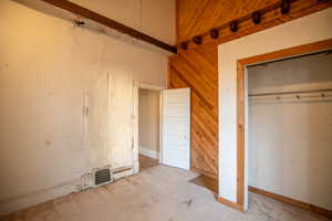 Unfurnished bedroom featuring wooden walls and baseboards