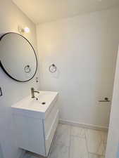 Half bath with vanity and light marble finish floors