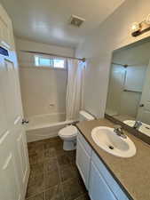 Bathroom with shower / bath combo with shower curtain, vanity, and a textured ceiling