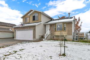 View of front facade featuring a garage, brick siding, and driveway