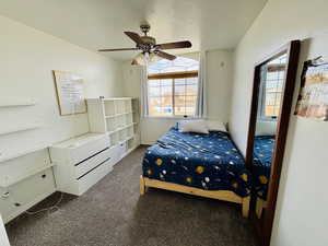 Carpeted bedroom with a textured ceiling, a ceiling fan.