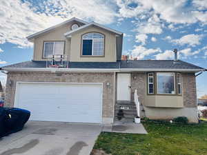 View of front facade with concrete driveway, a garage, a shingled roof, and brick siding