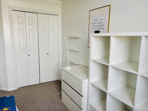 Bedroom with dark carpet and a closet