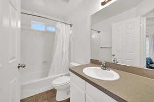 Bathroom featuring shower / bath combination with curtain, vanity, and tile flooring
