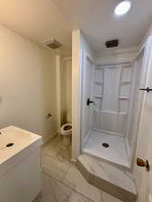 Bathroom featuring light marble finish flooring, a stall shower, and vanity