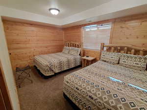 Bedroom with wood walls and carpet floors